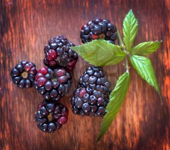 fresh blackberry and green leaves on the wooden table