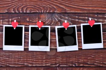 Blank instant photo and red hearts on wooden background