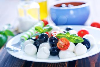 mozzarella cheese with tomato and olives on plate