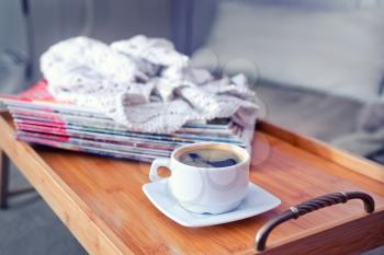 coffee and stack of magazins on wooden tray
