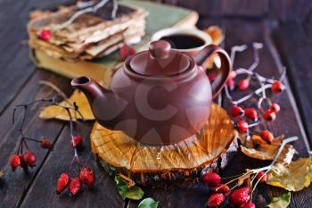 fresh tea in teapot on wooden board and on a table