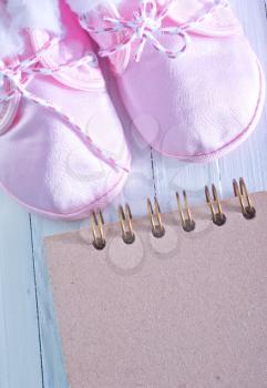 baby shoes and notepad for note on a table