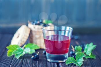 black currant juice in glass and on a table