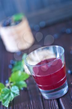 black currant juice in glass and on a table
