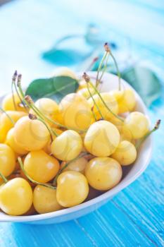 yellow cherry in bowl and on a table