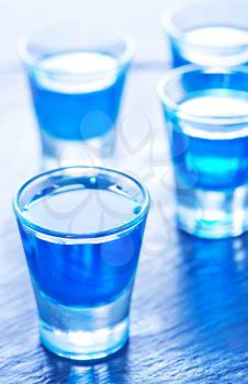 blue alcoholic drink into small glasses on a table