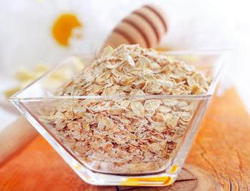 Raw oat flaks in the glass bowl