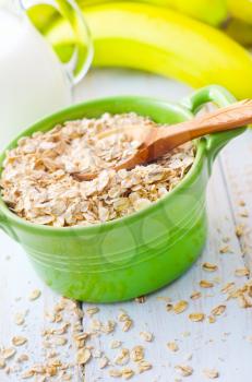 Oat flakes in the green bowl with banana and milk