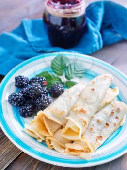 pancakes with blackberry on plate and on a table
