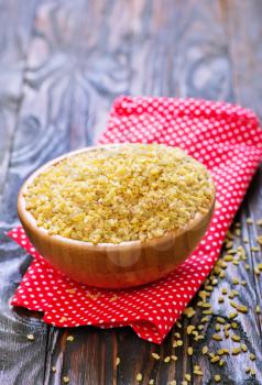 raw bulgur in bowl and on a table