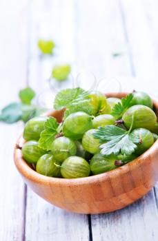 green gooseberry in bowl and on a table