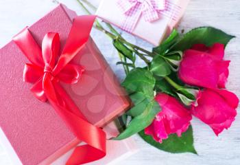 box for present and red roses on a table