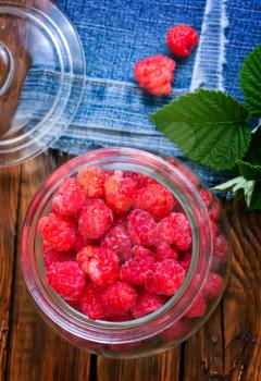 fresh raspberry in glass bank and on a table