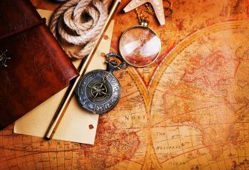 old notebook, loupe and compass on the map
