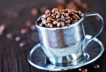 coffee beans in metal cup and on a table