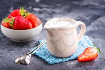 milk in jug and strawberry on a table