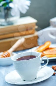 fresh tea in cup and pancakes on plate