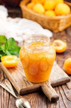 fresh apricot jam in glass bank and on a table