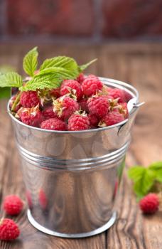 raspberry in metal bowl and on a table