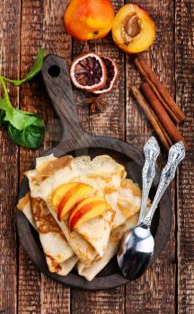 pancake with peach and cinnamon on the wooden board