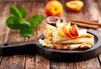 pancake with peach and cinnamon on the wooden board