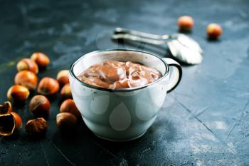 Homemade hazelnut spread or hot chocolate in cup with nuts and chocolate bar. 