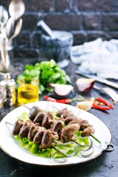 Fried hearts with spice. Chicken hearts kebab with salad on a plate top view