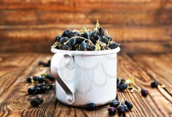 black currant in metal cup and on a table