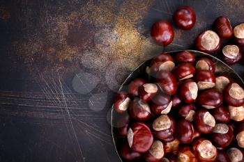 raw chesnuts on plate and on a table