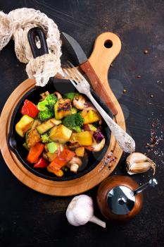 fried vegetables in pan and on a table