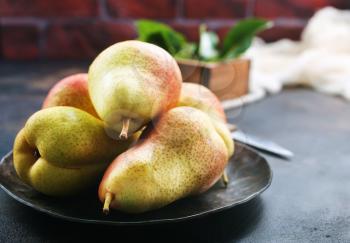fresh pears on plate and on a table