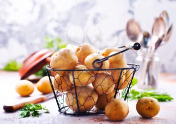 raw potato in metal basket and on a table