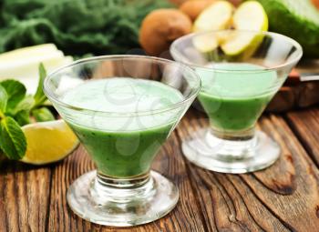Glass of green vegetable smoothie. Green vegetable smoothie and ingredients