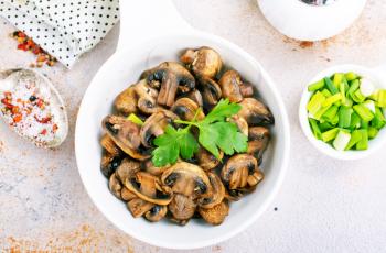  Vegan dish. Fried mushrooms and onion in the frying pan. European cuisine.