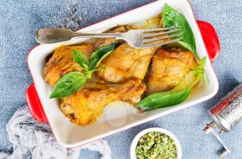 baked chicken legs with fresh basil leaves
