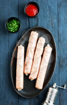 raw sausages with spice on metal plate