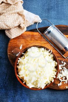 Grated cheese on wooden cutting board. cheese in bowl
