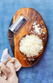 Grated cheese on wooden cutting board. cheese in bowl