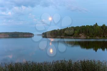 Ladoga lake at night under a blue cloudy sky with a bright moon