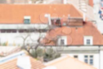 Blurred defocused urban abstract background of red tiled roofs of houses in old city in Europe, view of vintage houses with tile roofs in old town, blurred background.