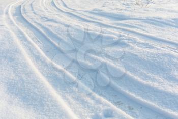 Country road on snow field, car tire tracks on white winter snow, perspective view, white winter landscape.