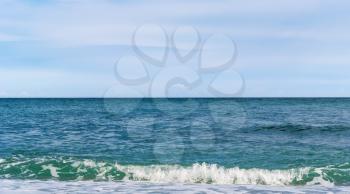 Blue sea with waves with sea foam under blue sky with clouds with in sunny day, beautiful nature landscape with horizon line
