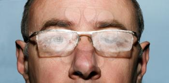 A man in dusty glasses on a gray background close-up