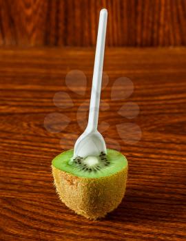 Half kiwi with a spoon on a wooden background
