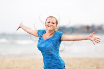 Beautiful young woman enjoying freedom. Free happy girl posing arms outstretched to the side and looking at the camera.