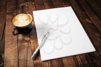 Blank branding template on vintage wooden table background. Letterhead, coffee cup and pen. Photo of blank stationery. Mock-up for design portfolios.