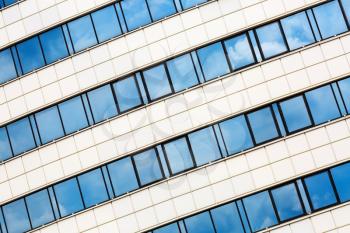 Close-up of modern architecture. Industrial building of steel and glass. Reflection of blue sky with clouds in the windows.