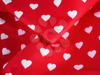 White hearts on a bright red fabric with pleats. Top view.