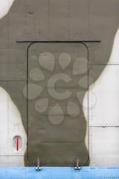 Abstract military painted matte metal background texture with rivets. Door of an old airplane. Vertical shot.