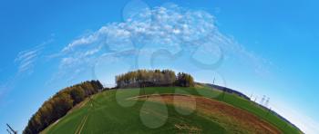 Summer landscape with blue sky, green field and forest on the horizon. Fish-eye effect.